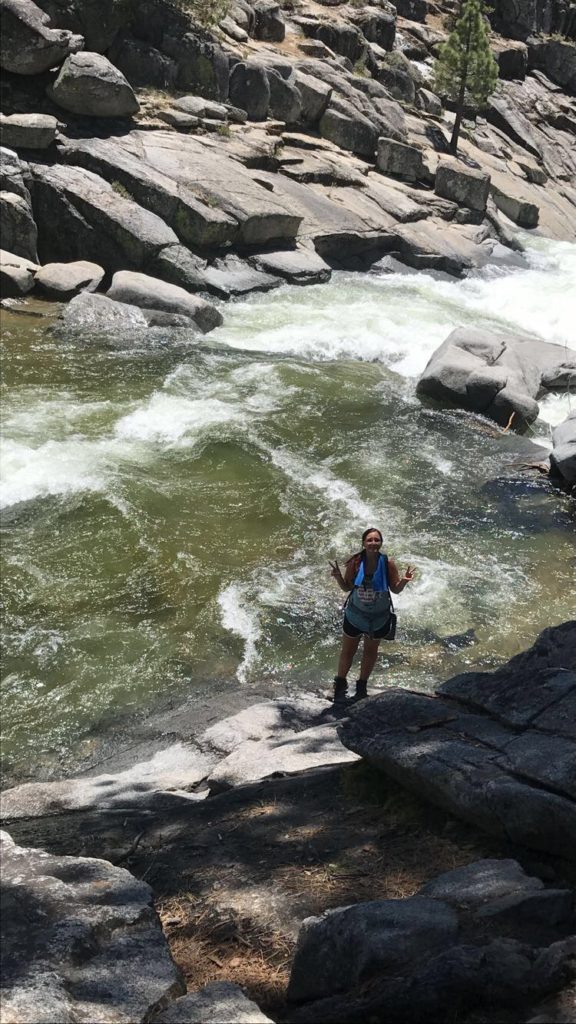 woman standing on rock right beside a creek