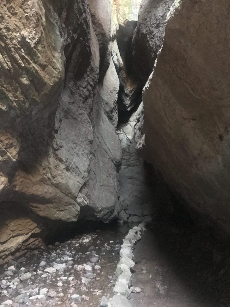 gray rocks line the trail that leads through a dark cave