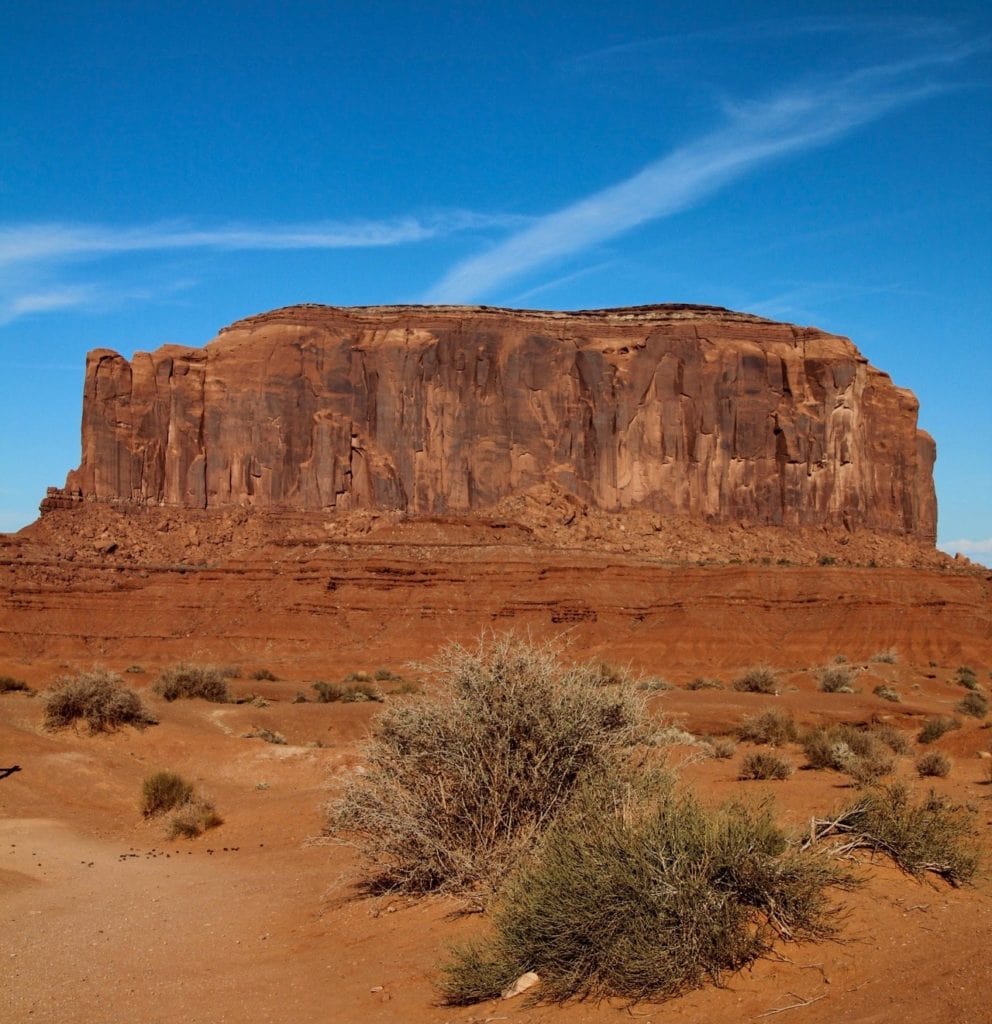 red-orange butte with desert plants and a blue sky