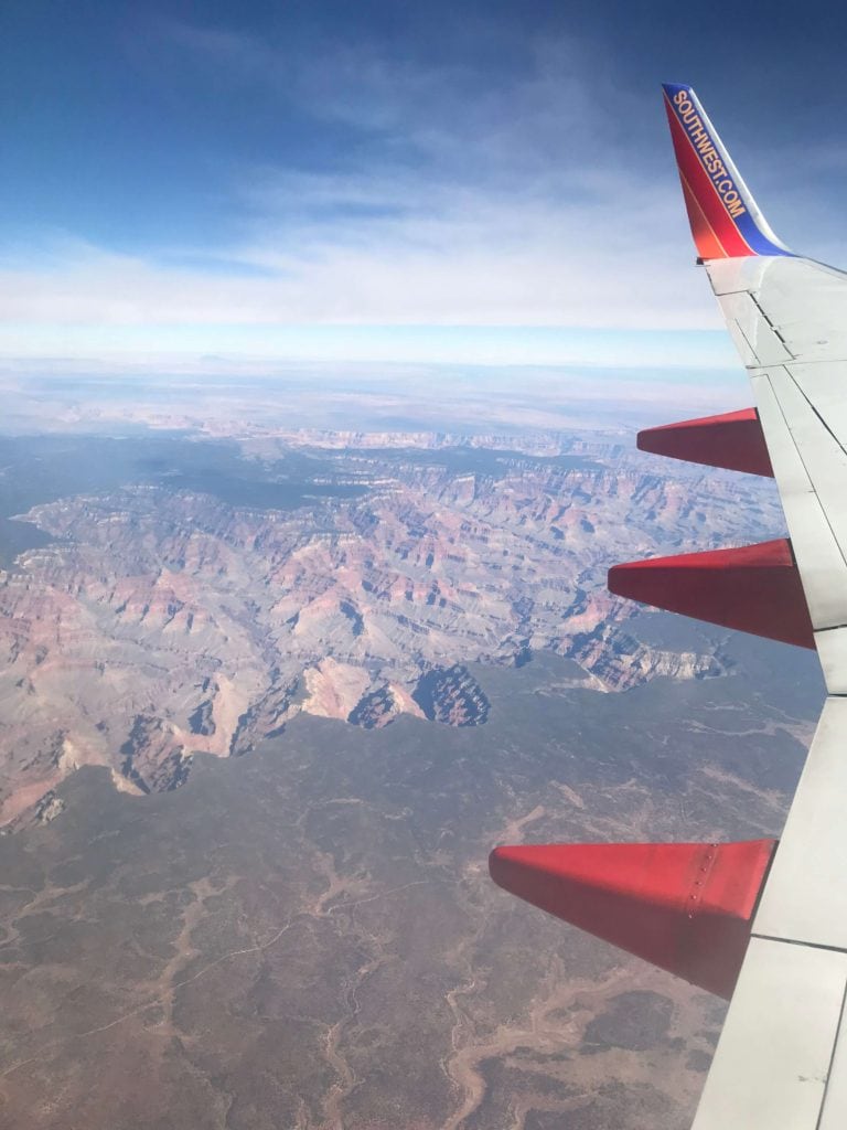 looking out of plane, can see the wing of the plane, overlooking the grand canyon